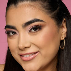 Modelo usando NYX Make 'Em Wonder™ Base de maquillaje en color 15 Buff with radiant soft matte finish and gold hoops.