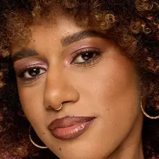 Modelo usando NYX Make 'Em Wonder™ Base de maquillaje en color 22 Medium with warm glow and gold hoop earrings.